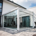 Weiße Terrassenüberdachung mit eleganten Glasschiebetüren.