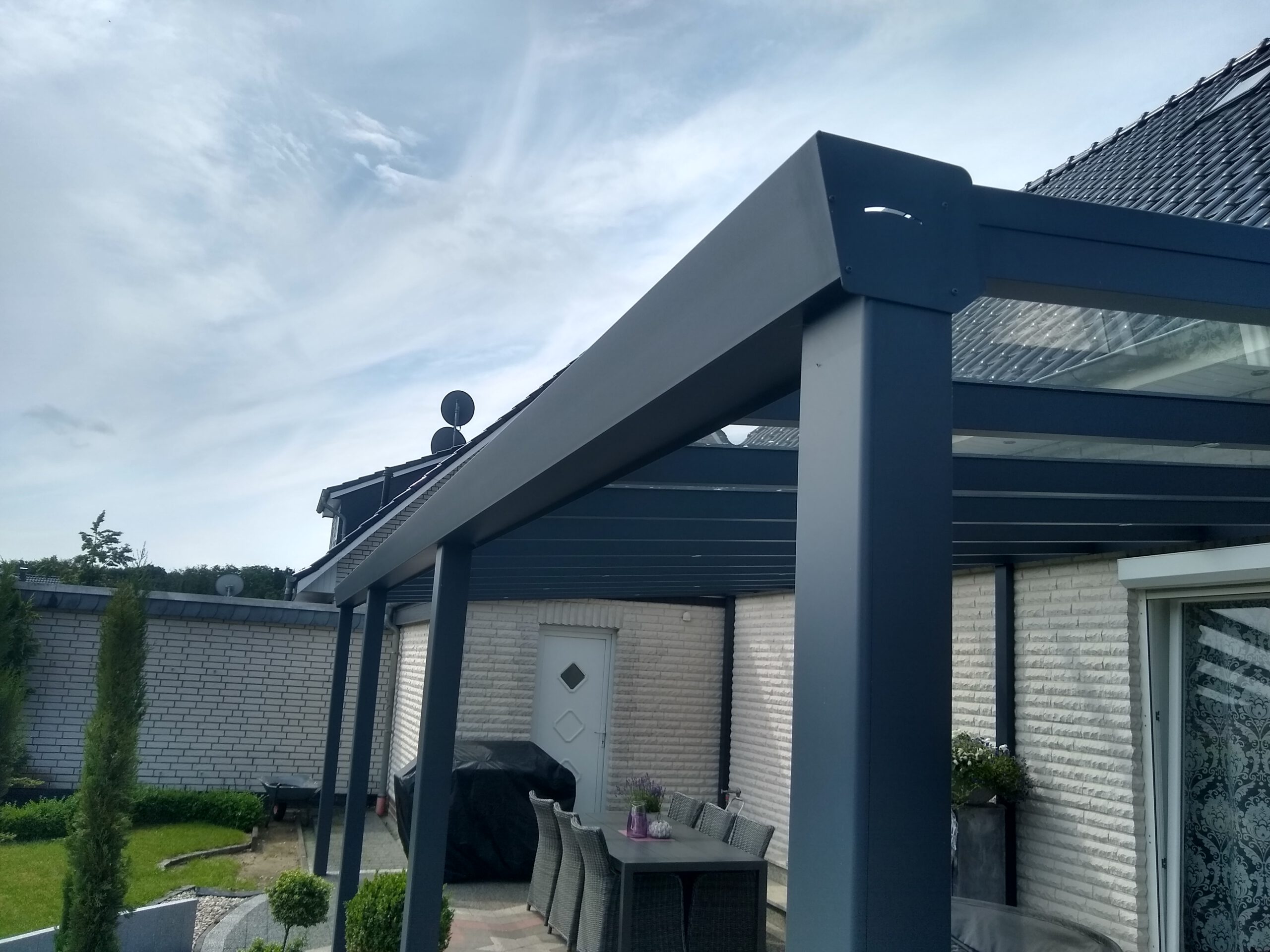 Braune Holzüberdachung mit Glasschiebewand – idealer Schutz und stilvolle Funktionalität für Ihre Terrasse. Alternativ bieten wir auch Terrassenüberdachungen in Anthrazit mit Glasschiebewand oder Carports aus Aluminiumsystemen für langlebigen und wetterfesten Schutz.